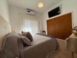 a bedroom with a bed and a flat screen tv at VIA VALENTINA "el deseo de volver" departamentos temporales sobre Av Eden centro in La Falda
