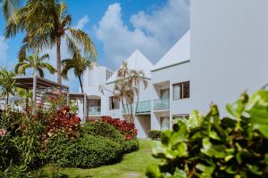 a white building with palm trees and plants at The Mill Resort and Suites in Palm-Eagle Beach