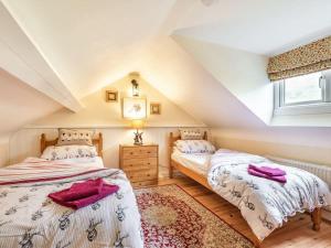 two beds in a attic bedroom with a window at Bwthyn Angell 