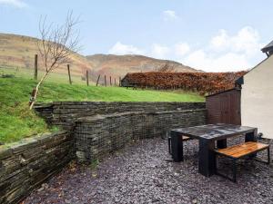 a stone wall with a table and a bench at Bwthyn Angell  +9 photos