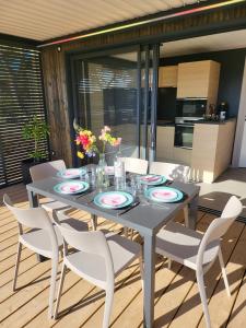 een eettafel met witte stoelen en bloemen erop bij Grand Cottage Cap d Agde in Agde