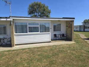 a house with chairs and a table in front of it at 103 Sunbeach South facing 2 bed chalet M and T chalets in Great Yarmouth