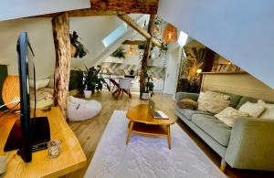a living room with a couch and a table at Nid douillet sous les toits avec jacuzzi in Bagnères-de-Bigorre
