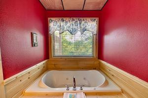 une baignoire dans une pièce rouge avec une fenêtre dans l'établissement The Bear Crossing by Venture Smoky Mountains, à Pigeon Forge 13 autres photos