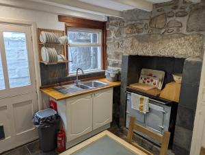 eine kleine Küche mit Spüle und Fenster in der Unterkunft Traditional Fisherman's Cottage with 3 bedrooms in Mousehole