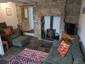 ein Wohnzimmer mit einem Steinkamin und einem Sofa in der Unterkunft Traditional Fisherman's Cottage with 3 bedrooms in Mousehole