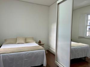 a white bedroom with a bed and a mirror at Casa Zara in Diamantina