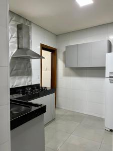 a white kitchen with a sink and a stove at Casa Zara in Diamantina