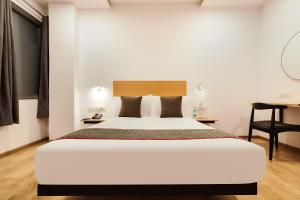 a bedroom with a large white bed and a desk at Super Townhouse Golden Avenue Road in Amritsar +29 photos