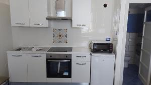 a kitchen with white cabinets and a stove and a microwave at Casa Pappalardo in Ravello