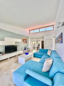 a living room with a blue couch and a tv at Estrella Del Sur Tauro Ocean Wiew Heated Pool in Mogán
