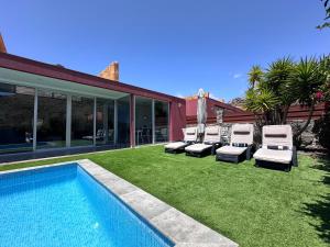 a yard with three lounge chairs and a swimming pool at Estrella Del Sur Tauro Ocean Wiew Heated Pool in Mogán