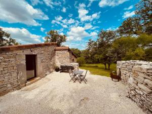 a building with two chairs and a dog standing next to it at Mas de Méjas Gîte La Casaline in Calvignac