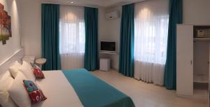 1 dormitorio con 1 cama con cortinas verdes y TV en Payidar HOTEL, en Estambul