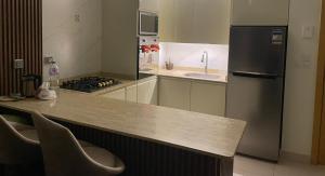 a kitchen with a refrigerator and a counter with chairs at Apartment at Marassi in El Alamein