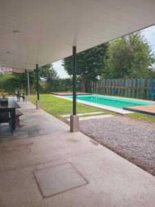 a swimming pool with a table and a pavilion at El Nido in San Nicolás de los Arroyos