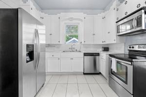 a kitchen with white cabinets and stainless steel appliances at Sinatra House Up Walk to Pleasure Pier and Fun in Galveston