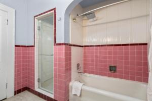 a bathroom with pink tile and a tub and a shower at Sinatra House Up Walk to Pleasure Pier and Fun in Galveston +18 photos