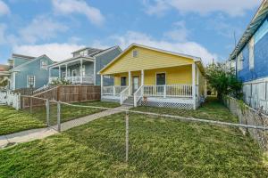 a yellow house with a fence in a yard at Welcome to Beach Lover Island Getaway in Galveston