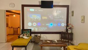 eine große Projektionsfläche in einem Wohnzimmer mit einem Tisch in der Unterkunft Cottage Palmier Rouge in La Trinité