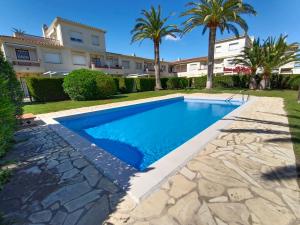 a swimming pool in front of a house with palm trees at Puerto Rico 6 in Empuriabrava +14 photos