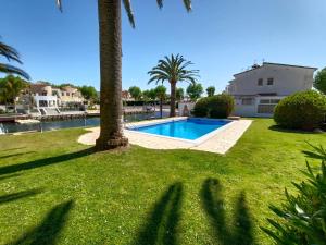 a shady yard with a swimming pool and palm trees at Puerto Rico 6 in Empuriabrava