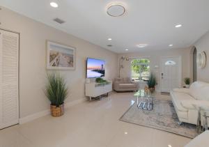 Una sala de estar con muebles blancos y un televisor de pantalla plana. en The Miami Gardens Getaway, en Miami Gardens