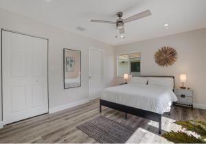 Un dormitorio blanco con una cama y un ventilador de techo. en The Miami Gardens Getaway, en Miami Gardens