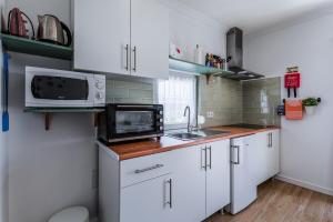 a small kitchen with white cabinets and a microwave at CASA DA FALÉSIA 28 - Casa in Peniche +36 photos