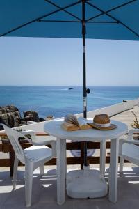 a table and chairs with an umbrella on the beach at CASA DA FALÉSIA 28 - Casa in Peniche