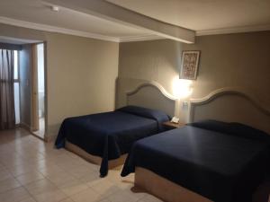 a hotel room with two beds and a lamp at Hotel del Paseo in Torreón