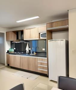 a kitchen with wooden cabinets and a refrigerator at Refúgio Manhattan Flat - Silencio, espaço e ao lado do shopping in Campo Grande