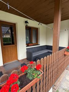 a porch with a couch and red flowers on it at Pokoje gościnne Kozica in Zakopane