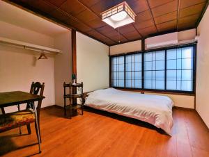 a bedroom with a bed and a desk and windows at Tsugaru House1 in Aomori