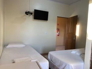 a room with two beds and a television on the wall at Junior Hotel in Anapu +2 photos