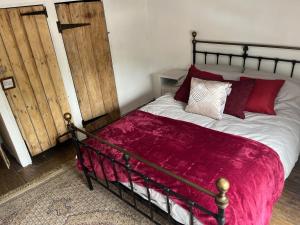 a bedroom with a large bed with red pillows at Harleston Norfolk Suffolk border Historic Cottage in Harleston +2 photos