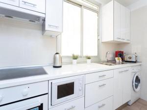 a white kitchen with white cabinets and a sink at Trip Medano England Centro in El Médano