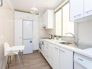 a white kitchen with a sink and a refrigerator at Trip Medano England Centro in El Médano +16 photos
