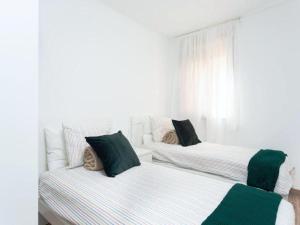 two beds in a white room with green pillows at Trip Medano England Centro in El Médano