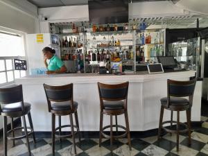 a woman standing behind a bar with four chairs at Beach Studio 24 at Sandcastles in Ocho Rios