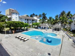 a large swimming pool with chairs and palm trees at Beautiful Beachview 2 Bebroom Loft at Sandcastles in Ocho Rios