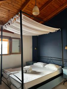 a bedroom with a canopy bed with white sheets at Maroulios Apartment in Elafonisos