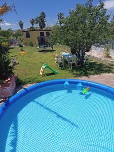 een blauw zwembad met een tafel en een speeltuin bij Villa Mirko in Vaccarizzo - Delfino