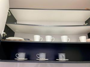 a shelf with white cups and plates on them at Apartamento 3 quartos, conforto e espaço no centro in Foz do Iguaçu