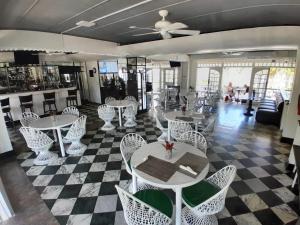 a restaurant with white tables and chairs on a checkered floor at Beach Studio 21 in Ocho Rios