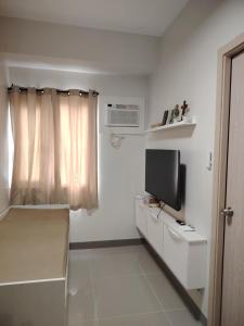 a small white room with a tv and a window at Charm Residences Building E in Manila