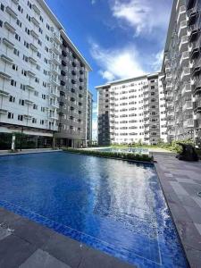 a large swimming pool in front of two large buildings at Charm Residences Building E in Manila