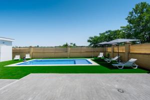 a swimming pool with two chairs and an umbrella at Resort Circuito Sevilla in Carmona