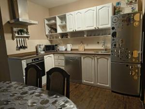 Una cocina con gabinetes blancos y un refrigerador de acero inoxidable. en Apartment I&M, en Osijek