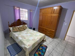 a bedroom with a bed and a wooden dresser at Casa Lilás in Goiás